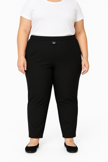 Person wearing black pants and a white top on a plain background