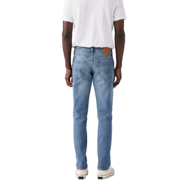 Person wearing blue jeans and a white t-shirt on a plain background