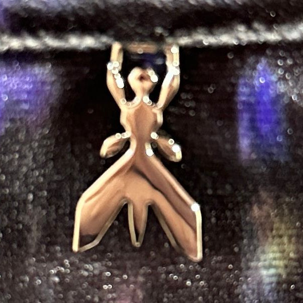 Silver ant-shaped pendant on a reflective black surface