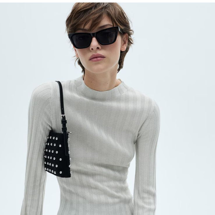 Woman wearing a beige knitted dress with sunglasses on a white background