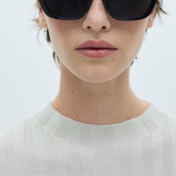 Woman wearing black sunglasses with a white background on a Mango website page.