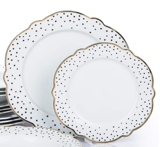 Set of white dinner plates with gold and black dot patterns on a white background