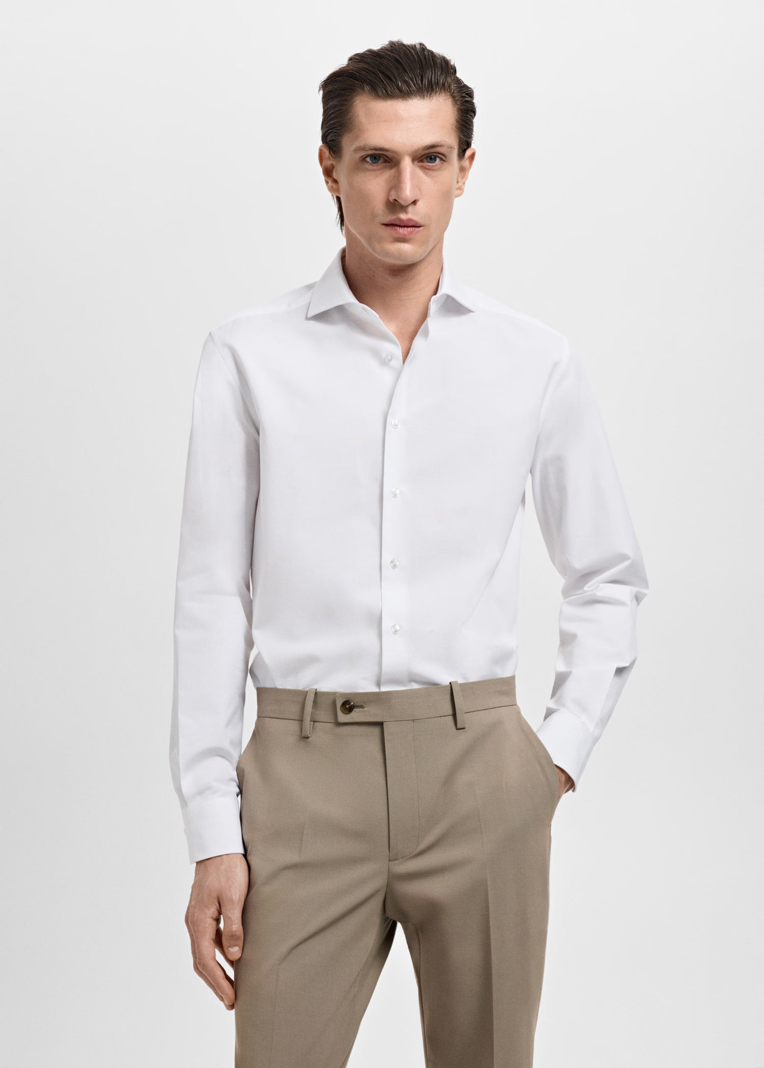 Man wearing a white dress shirt and beige pants on a white background