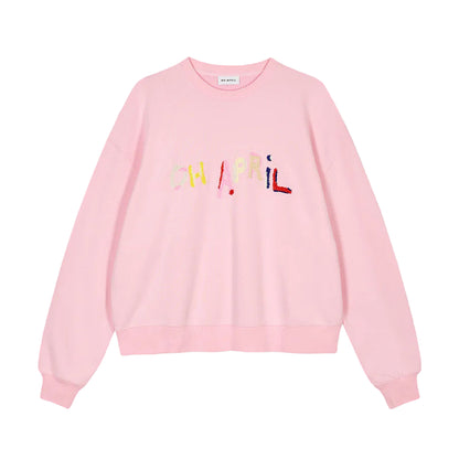 Pink sweatshirt with colorful text on a gray background