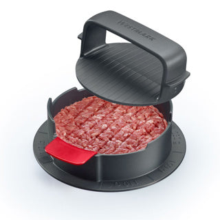 Hamburger meat being shaped in a black burger press with a red handle on a white background.