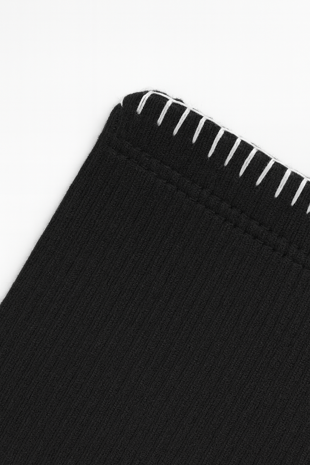 Close-up of black fabric with white stitching on a white background
