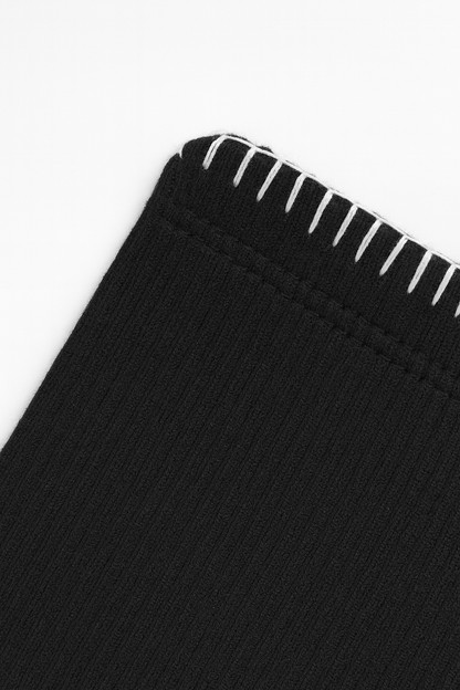 Close-up of black fabric with white stitching on a white background