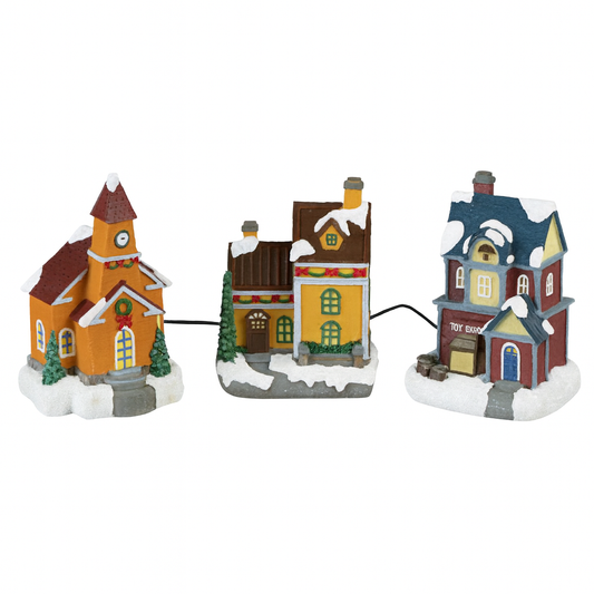 Three colorful miniature houses with snow on a white background