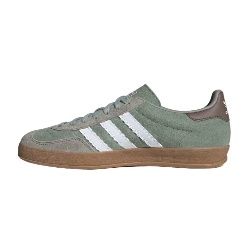 Green Adidas sneaker with white stripes on a light gray background
