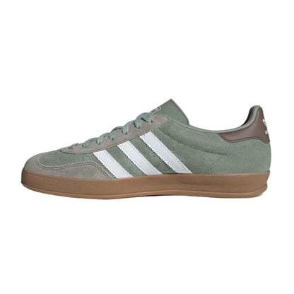 Green Adidas sneaker with white stripes on a light gray background