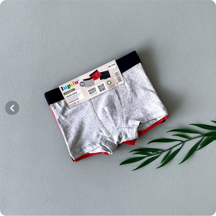 White boxer briefs with a red interior on a gray surface, displayed on a computer screen.