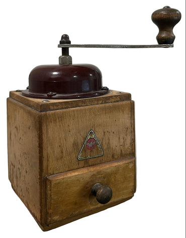 Wooden coffee grinder with a red triangle logo on a textured white background
