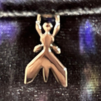 Silver ant-shaped pendant on a reflective black surface