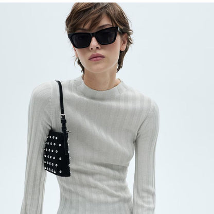 Woman wearing a beige knitted dress with sunglasses on a white background