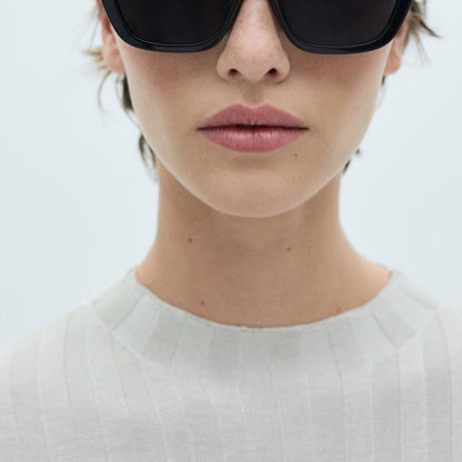 Woman wearing black sunglasses with a white background on a Mango website page.