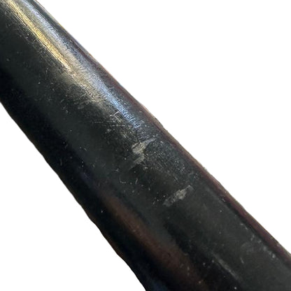 Close-up of a metal rod on a reflective surface with pink material in the background