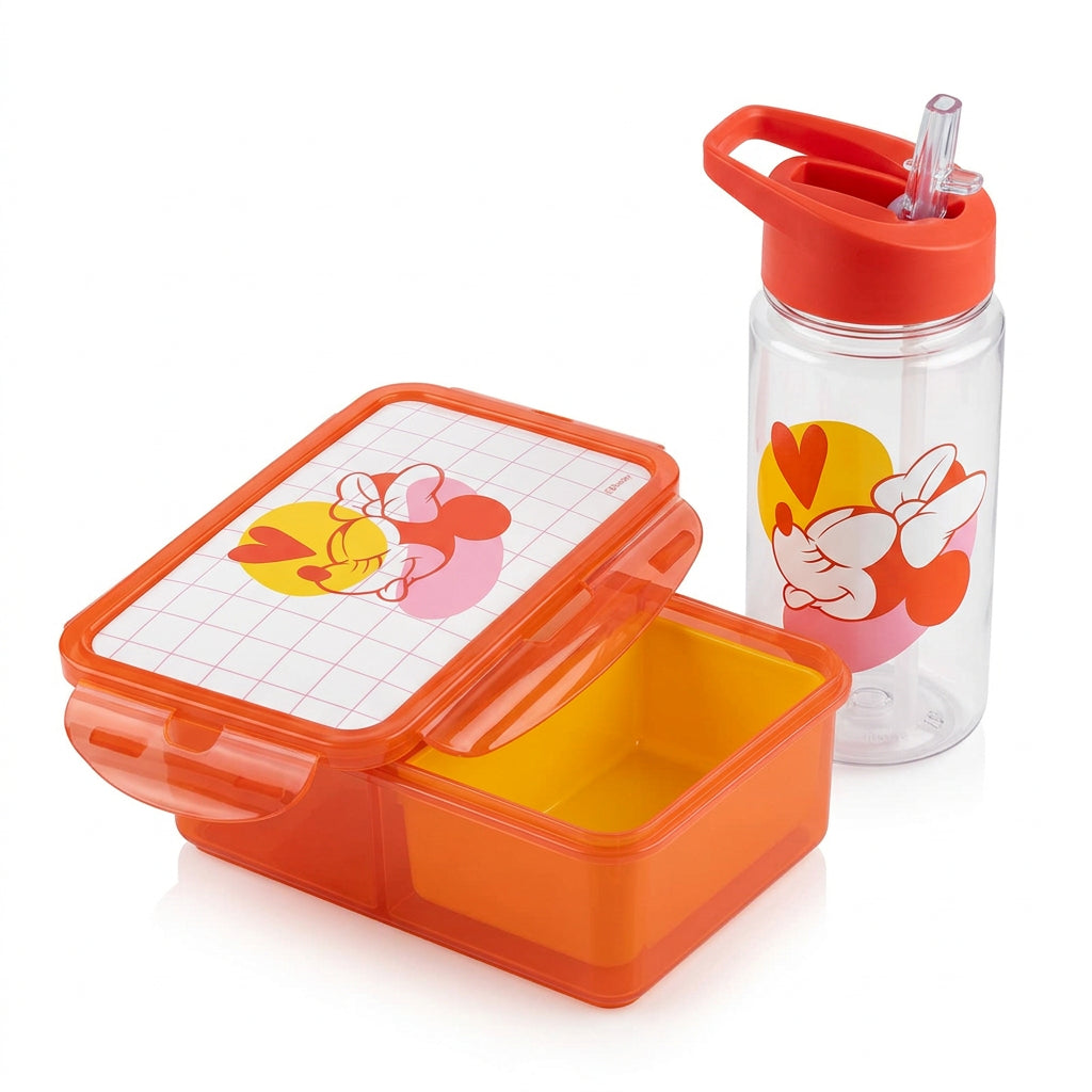 An orange plastic lunch box with a cartoon Minnie Mouse lid design, shown open on a wooden desk next to a laptop, mouse, water bottle, and other office items.