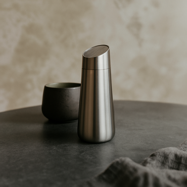 Two metallic containers on a dark surface with a beige background