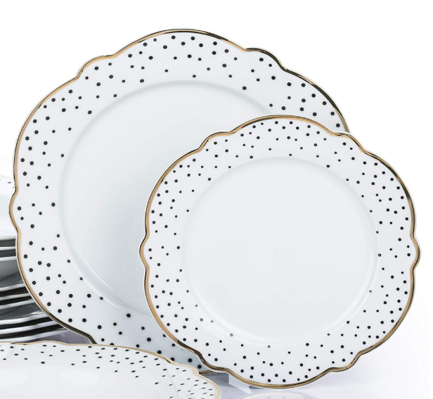 Set of white dinner plates with gold and black dot patterns on a white background